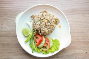 Pork fried rice served in a restaurant with wooden floor tables with tomatoes, cucumbers, scallions, fried rice, delicious food made from steamed rice, top view photo