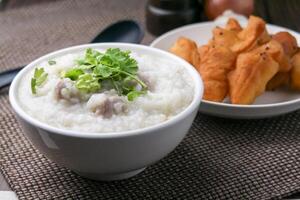 Close up Rice porridge ,congee with minced pork and ginger in white bowl photo