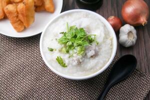 Hot Chinese porridge rice porridge with minced pork meatballs for breakfast on a wooden table. photo