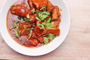 Chinese Red Soup Pork Ribs served on a white plate, a popular Chinese dish, made from sliced pork ribs and tomato sauce. photo