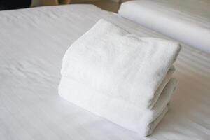 Selective focus on white fresh towels in hotel bed. Room service concept. Closeup white on new bedding and personal hygiene items. photo