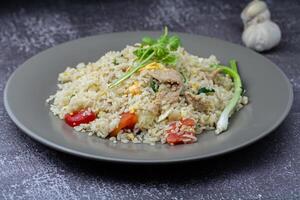 frito arroz con pollo y vegetales en un plato en un oscuro antecedentes foto