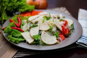 Spicy Glass Noodle Salad with Vietnamese Sausage  served in a gray plate Put on a wooden table and various vegetables. photo