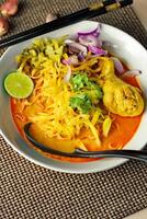 Khao soy Recipe, Curried Noodle Soup with Chicken Served on white Bowl, Thai Food, Curry Noodle, Thai Noodle, Northern Food. photo