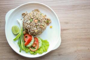 Pork fried rice served in a restaurant with wooden floor tables with tomatoes, cucumbers, scallions, fried rice, delicious food made from steamed rice, top view photo