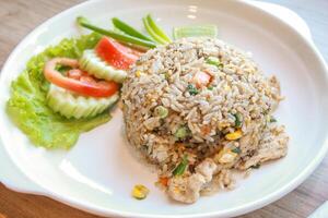 Pork fried rice served in a restaurant with wooden floor tables with tomatoes, cucumbers, scallions, fried rice, delicious food made from steamed rice. photo