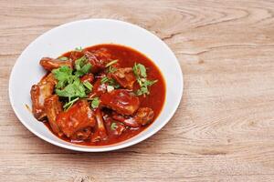 Chinese Red Soup Pork Ribs served on a white plate, a popular Chinese dish, made from sliced pork ribs and tomato sauce. photo