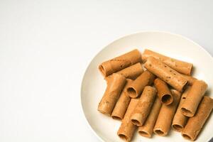 Crispy egg roll or crispy golden curl placed in a white plate, white background. Isolated. photo