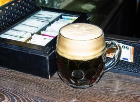 A mug of dark beer foaming on a wooden table. photo