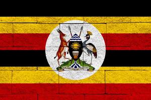 bandera y Saco de brazos de república de Uganda en un texturizado antecedentes. concepto collage. foto