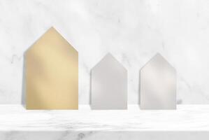 Old Paper Houses on Marble Table with White Wall Background with Tree Shadow, Suitable for Product Presentation Backdrop, Display, and Mock up. photo