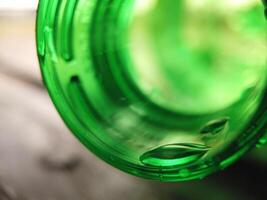 cerca arriba soltar de agua en verde botella labio. foto