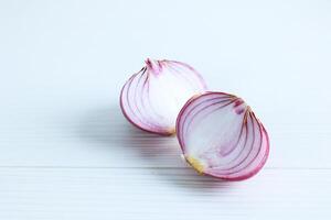 Peeled and Halved Red Onion on a White Wood Table Two Pieces of Peeled Purple Onion photo