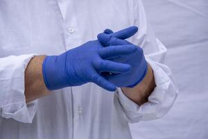 Hands of a woman in a white coat and blue latex gloves. photo