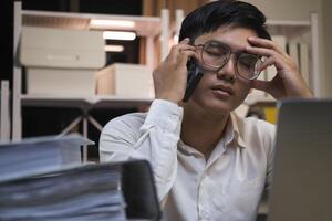 Asian young tired staff businessman using desktop computer having overwork project overnight in office. photo