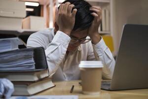 Asian young tired staff businessman using desktop computer having overwork project overnight in office. photo