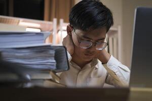 Asian young tired staff businessman using desktop computer having overwork project overnight in office. photo