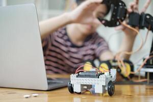 Asian teenager doing robot project in science classroom. technology of robotics programing and STEM education concept. photo