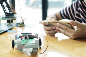 Asian teenager doing robot project in science classroom. technology of robotics programing and STEM education concept. photo