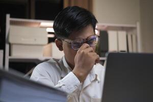 Exhausted young man with laptop in office. photo