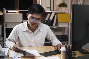 Young businessman working overtime on a desk at night. photo