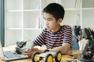 Asian teenager doing robot project in science classroom. technology of robotics programing and STEM education concept. photo