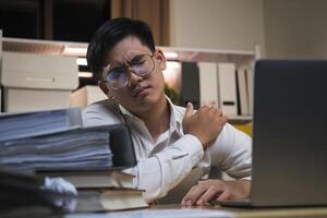 Asian businessman overtime work and feel shoulder pain in the office. photo