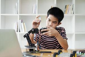 Asian teenager doing robot project in science classroom. technology of robotics programing and STEM education concept. photo