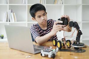 Asian teenager doing robot project in science classroom. technology of robotics programing and STEM education concept. photo