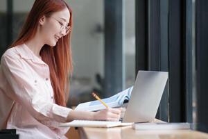Young collage student using computer and mobile device studying online. photo