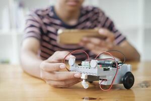 Asian teenager doing robot project in science classroom. technology of robotics programing and STEM education concept. photo