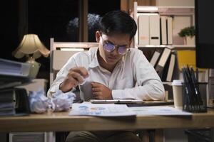 Young businessman working overtime on a desk at night. photo