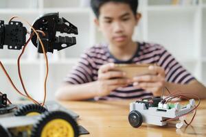 Asian teenager doing robot project in science classroom. technology of robotics programing and STEM education concept. photo