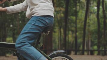 Relajado y relajado joven asiático mujer en casual confortable ropa montando un bicicleta en el bicicleta carril en el parque. pasatiempo y ejercicio concepto video