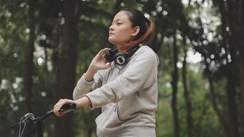 chilling e rilassato giovane asiatico donna nel casuale comodo Abiti equitazione un' bicicletta su il bicicletta corsia nel il parco. passatempo e esercizio concetto video