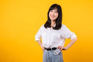 Captivating image of Asian young woman wearing white shirt and denim jeans, confidently holding cash from her shirt pocket. Fashion meets financial empowerment. Perfect for finance and fashion themes. photo