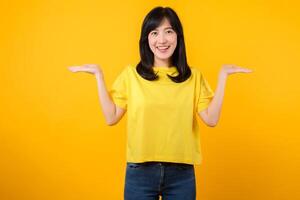 Confident Asian woman pointing to free copy space isolated on yellow studio background photo