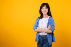 Radiate confidence with captivating portrait. A young Asian woman wearing a blue shirt showcases happy smile while crossing her arms. Perfect for conveying a sense of self-assurance and determination. photo