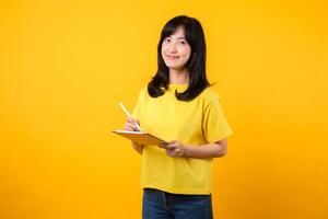 experiencia el alegría de educación tecnología con retrato. un joven asiático mujer vistiendo un amarillo camiseta y mezclilla pantalones vitrinas un contento sonrisa mientras utilizando digital tableta. educación tecnología concepto. foto