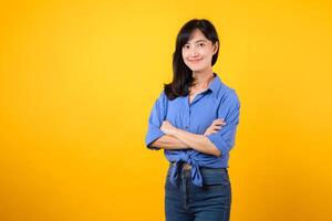 Radiate confidence with captivating portrait. A young Asian woman wearing a blue shirt showcases happy smile while crossing her arms. Perfect for conveying a sense of self-assurance and determination. photo