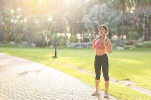 Female jogger. Active 30s young Asian woman in pink sportswear enjoys a morning workout in nature. active and live a healthy lifestyle concept. photo