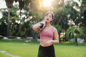 Happy young 30s asian woman wearing pink sportswear and jogging in nature. Captures the joy of a morning run and would be perfect for any project promoting fitness, health, or a healthy lifestyle. photo