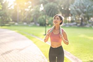 ajuste contento sonrisa 30s joven asiático mujer en ropa de deporte disfruta refrescante puesta de sol correr en naturaleza. el silueta de figura en contra el ajuste Dom es hermosa vista. aptitud física, salud, o motivación concepto. foto