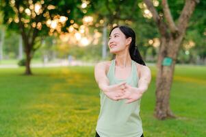 Female jogger. Fit young Asian woman with green sportswear stretching muscle in park before running and enjoying a healthy outdoor. Fitness runner girl in public park. Wellness being concept photo