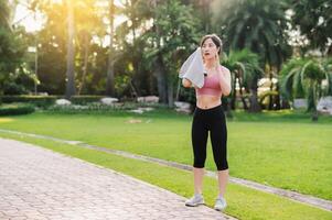 Happy young 30s asian woman wearing pink sportswear and jogging in nature. Captures the joy of a morning run and would be perfect for any project promoting fitness, health, or a healthy lifestyle. photo