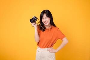 alegre joven asiático mujer en 30s vistiendo naranja camisa y participación cámara, Listo a capturar recuerdos. Perfecto para ilustrando felicidad, fotografía, y el alegría de capturar especial momentos foto