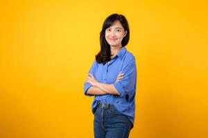 Radiate confidence with captivating portrait. A young Asian woman wearing a blue shirt showcases happy smile while crossing her arms. Perfect for conveying a sense of self-assurance and determination. photo