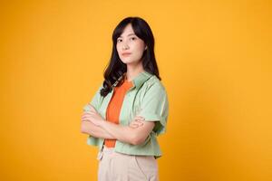 Radiate confidence portrait of young Asian woman wears pastel green shirt on orange shirt confidently crossing her arms. Perfect for capturing a sense of self assurance and empowerment. photo