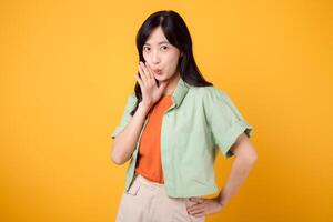 Capture young Asian woman 30s wearing a green shirt on an orange background, enthusiastically shouting with excitement. Explore the concept of discount shopping promotion with this vibrant image. photo