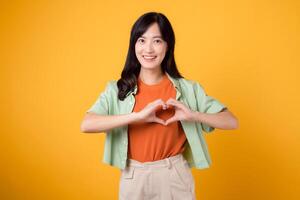 healthcare and wellness with an Asian young woman in her 30s, wearing a green shirt. showcases a heart hand gesture on her chest against a yellow background, embodying the concept of body wellness. photo